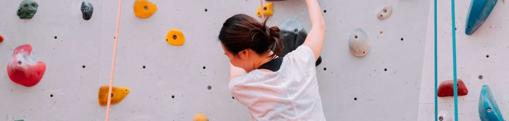 image of woman on climbing wall illustrating one type of risk management