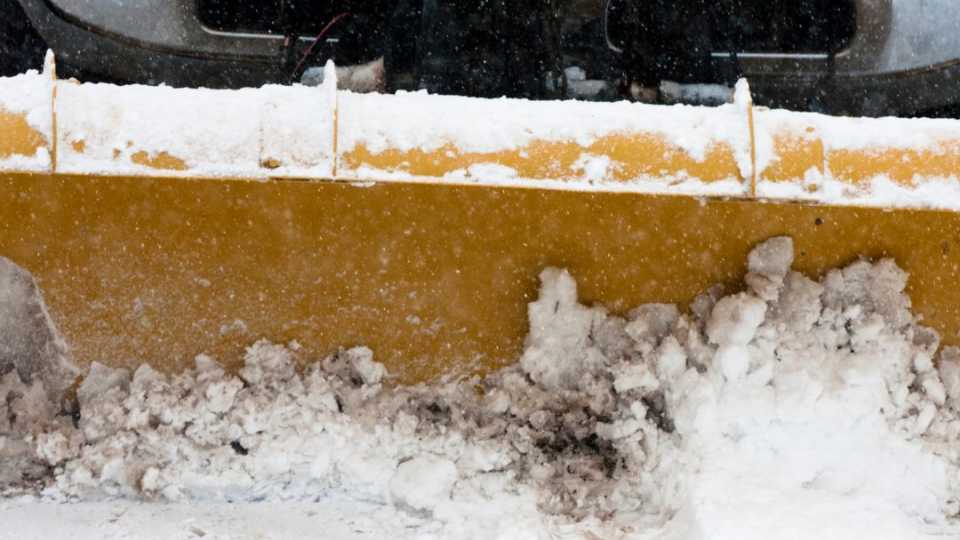 Image of a plow clearing snow from a recreation facility parking lot.