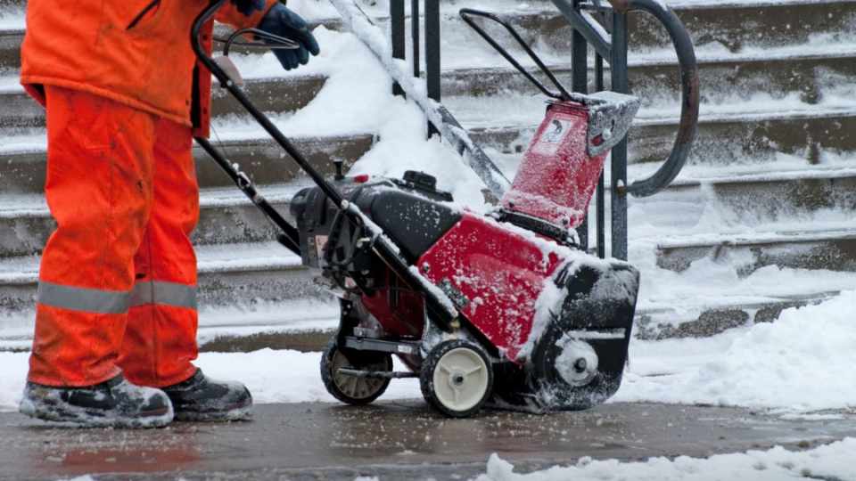 Image of maintenance worker clearing snow in front of a recreation facility